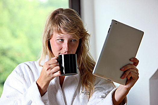 年轻,女人,穿,长袍,喝,杯子,咖啡,早晨,坐,厨房,读,上网,报纸,电脑