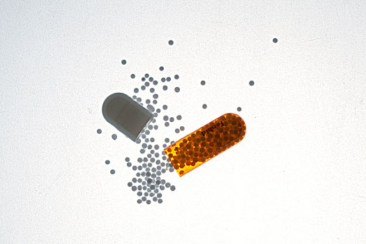 一粒胶囊被拆开白色的药粒散落开来