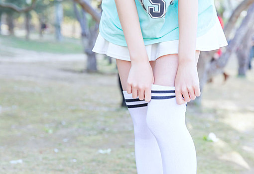 穿短裙露出美丽大腿的女孩用好看的手提过膝白色学生袜