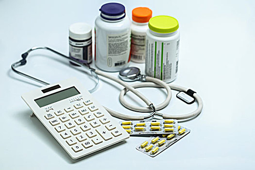 计算器,听诊器,胶囊和药瓶放在白色背景上