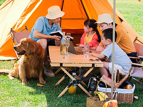快乐的四口之家和宠物狗在户外露营