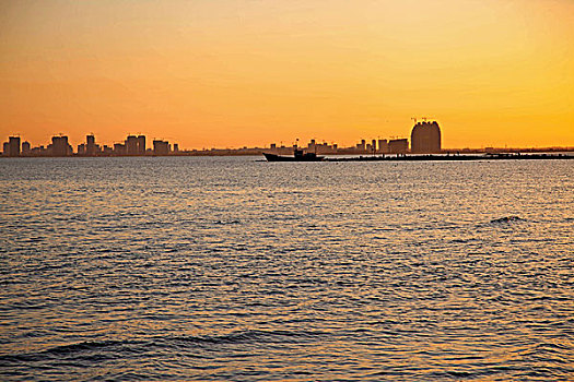 红色夕阳照映下的大海和城市的海岸线