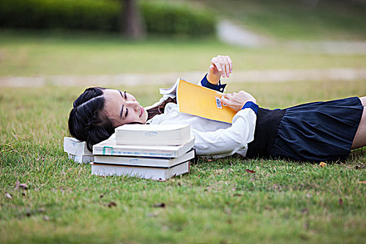 大学生躺在草地上看书