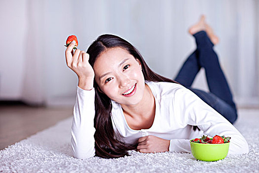 休闲女士趴在地毯上吃草莓