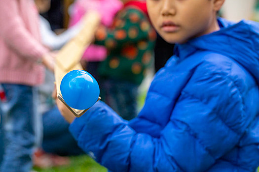 一群小孩在室外公園,玩著传球接龙游戏