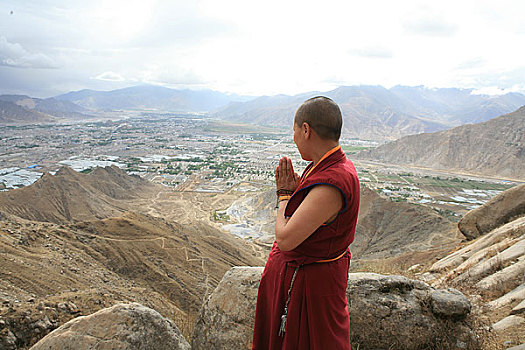 西藏米穷日寺的一个尼姑在遥望山下大布达拉宫祈祷