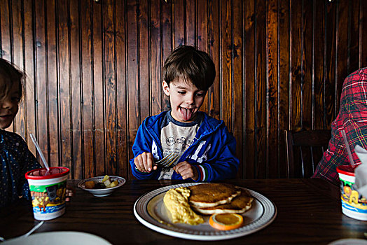 男孩,棕发,坐,室内,桌子,正面,盘子,食物,伸舌头