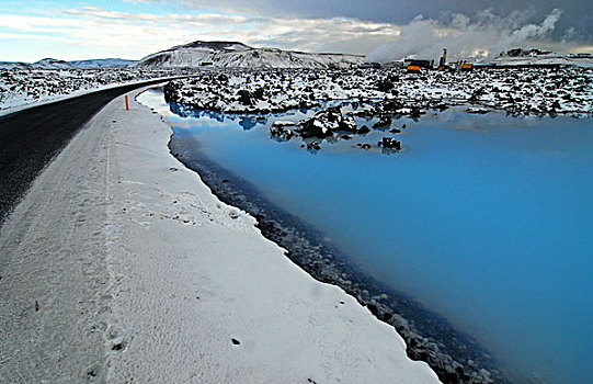 iceland,blue,lagoon,road,along,color,lake,with,snowy,lava,rock,in,the,background