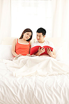 年轻夫妻躺在床上看书