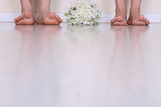 两双脚旁放着一束鲜花