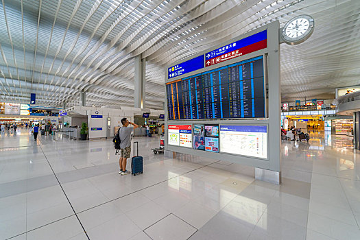 在香港国际机场二号客运大楼,旅客们正在查看航班信息