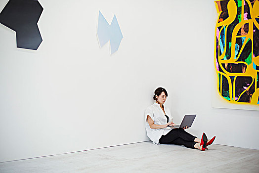 女人,短小,黑发,穿,白衬衫,黑色,裤子,红色,高跟鞋,坐在地板上,画廊,拿着,笔记本电脑