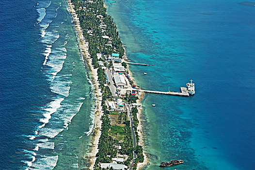 tuvalu,funafuti,aerial,view,of,shoreline,along,the,landscape,with,trees,and,houses,boat,anchored,by,jetty