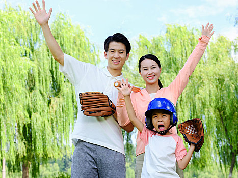 快乐的三口之家在公园打棒球