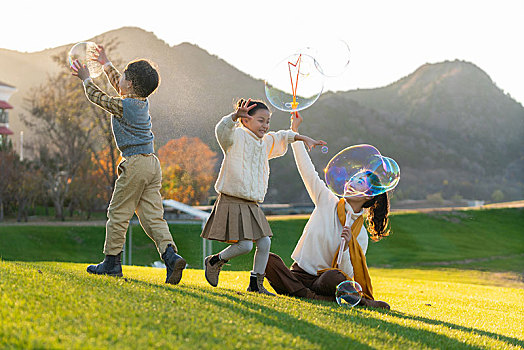 母亲和孩子们在草地上玩泡泡