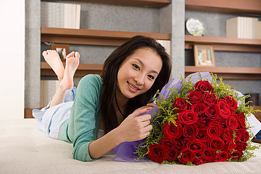 一个女人抱着一束鲜花趴在床上