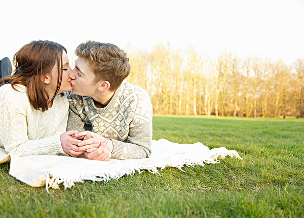 年轻夫妇躺在草地上,接吻
