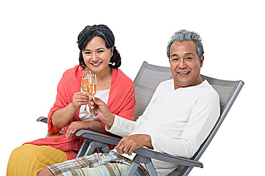 快樂的老年夫婦坐在沙灘椅上喝香檳酒