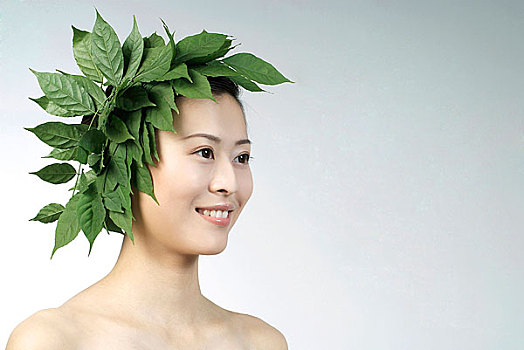 用绿叶装饰头部微笑的东方女人头像