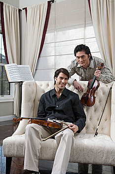 两位先生拿着小提琴对着镜头微笑