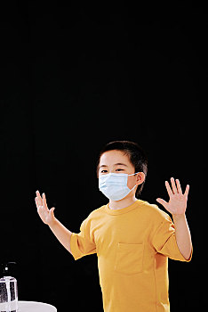 戴口罩的小男孩使用免洗洗手液后展示双手