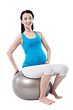 在白色背景下练瑜伽的孕妇