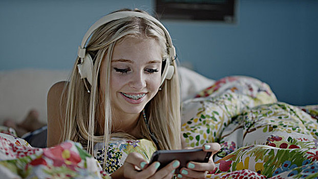 高兴,女孩,听,耳机,看,手机,床