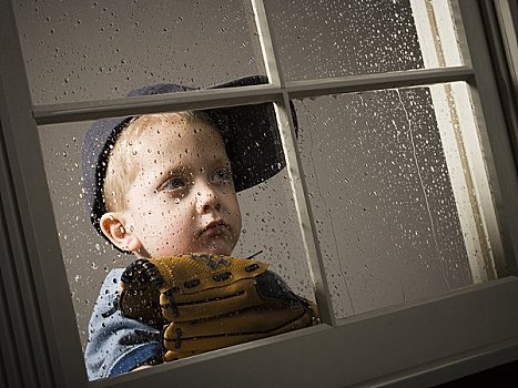男孩,棒球手套,向窗外看,雨天