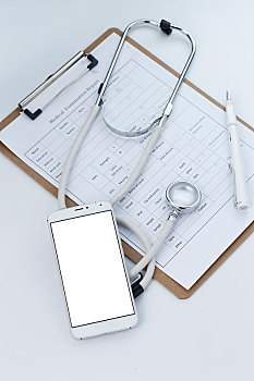 手机,听诊器和病历夹放在白色桌面上