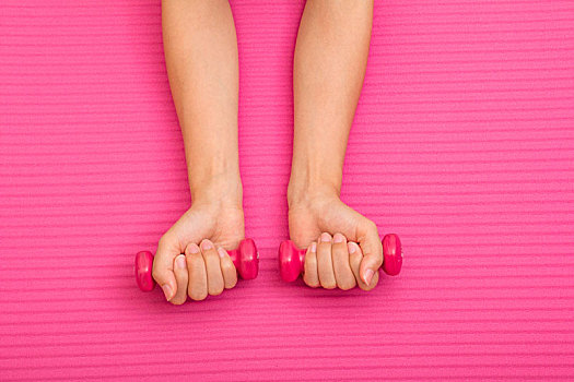 女生使用粉红色哑铃锻炼手部力量