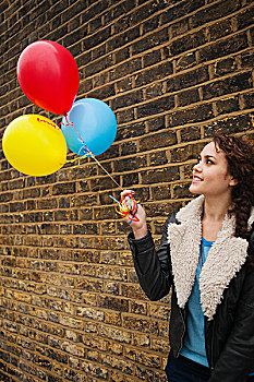 女青年,拿着,彩色,气球,砖墙