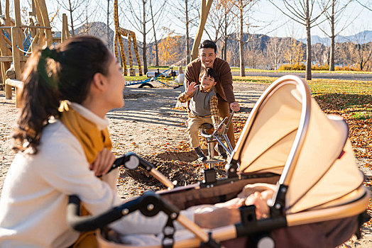年轻家庭推着婴儿车散步