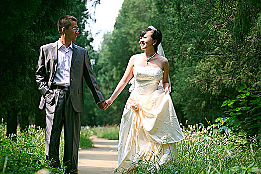 手拉手走在林荫道上的新郎和新娘