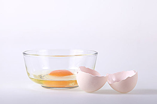 打开的鸡蛋壳和放着鸡蛋黄的玻璃碗