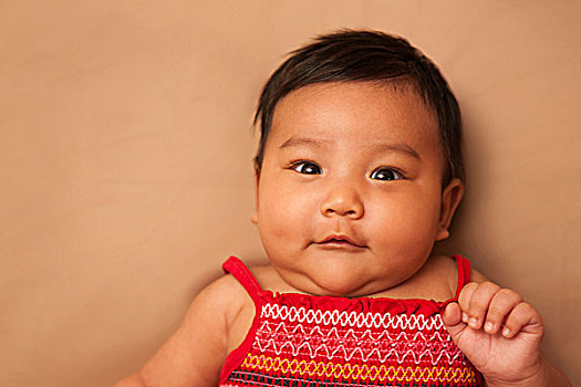 亚洲人,婴儿,躺,穿,红裙,看镜头,微笑,棚拍,褐色背景