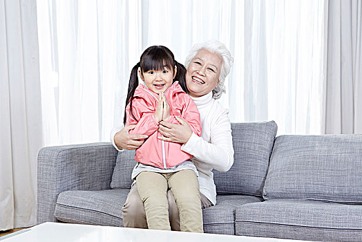 奶奶抱着孙女坐在沙发上