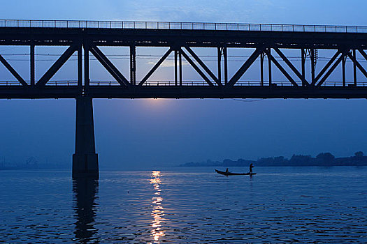 黑龙江哈尔滨日落时分的松花江大桥下,江上打渔