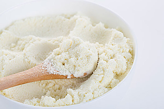 奶粉在白色的碗中,以及一个小木勺