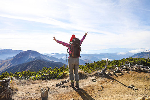 一个女性徒步旅行者在山顶张开双臂