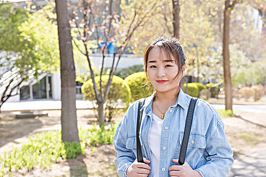 年轻漂亮的女学生背着包在校园里