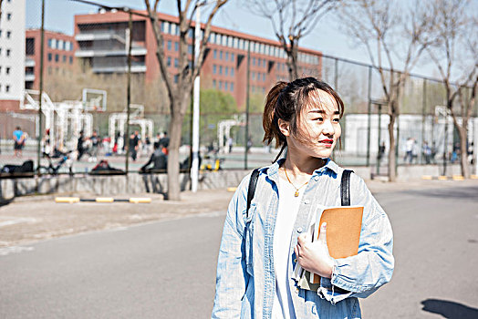 年轻漂亮的女学生背着包在校园里