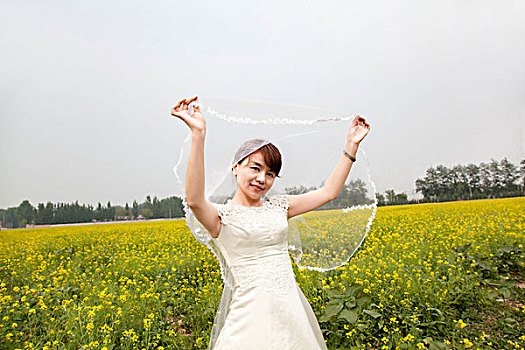 穿着婚纱站在油菜花田的女人