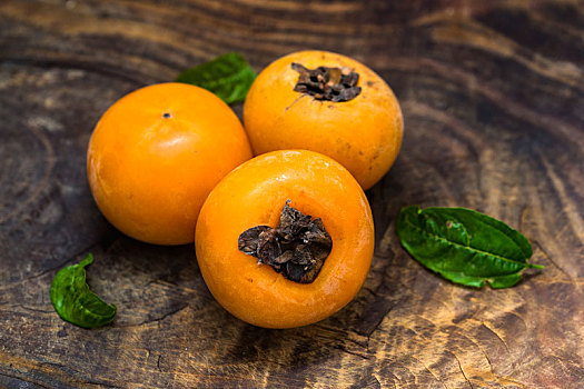 成熟的香蜜甜柿子摆放在陈旧的木板上