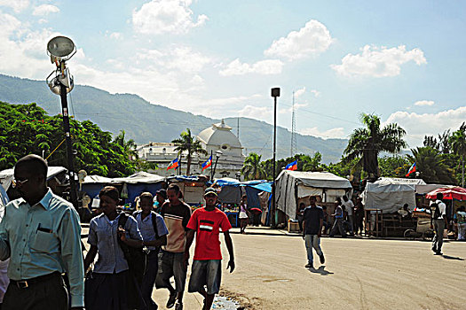 haiti,port,au,prince,champs,de,mars,camp,young,adults,walking,in,front,of,destroyed,presidential,palace