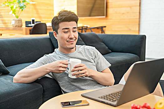 年轻男子坐在沙发边使用电脑