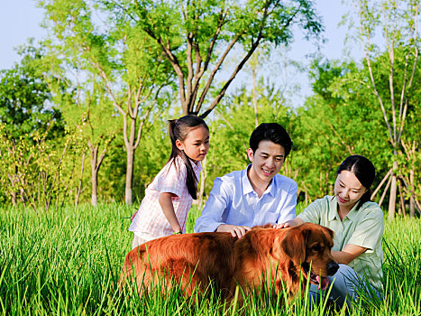 快乐的三口之家和宠物狗在公园玩耍