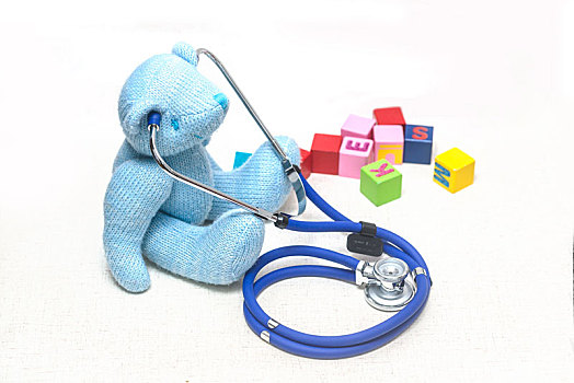 地板上毛绒玩具熊,听诊器与积木,寓意儿童健康,医疗保健概创意图