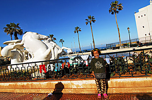 algeria,alger,girl,playing,by,railing,with,socks,drying,on,it,sculpture,of,horse,and,swimming,pool,in,background