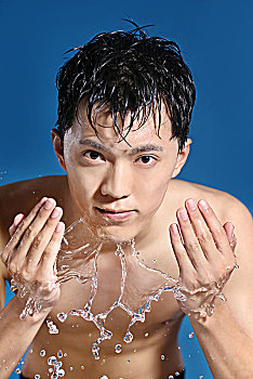 蓝色背景下面清洁面部的亚洲男青年