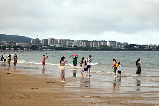 游客漫步沙滩赶海拾贝感受大海风情